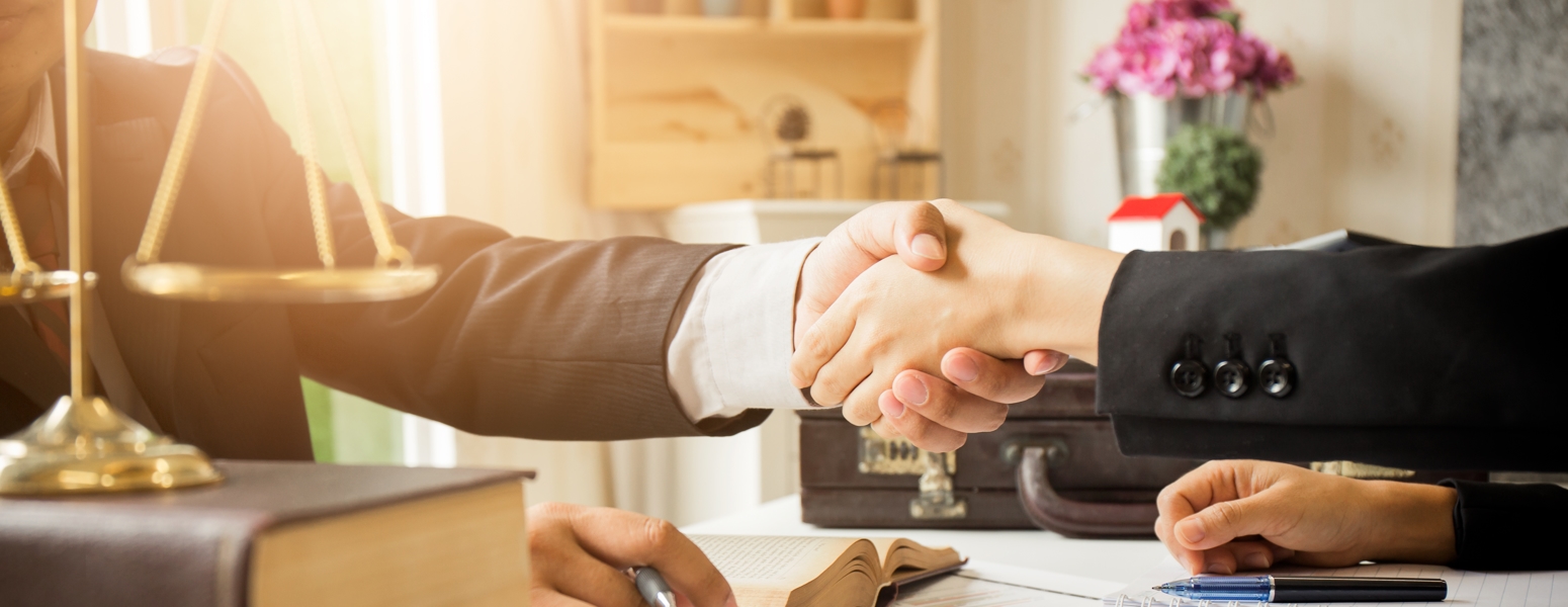 Two people shaking hands over a desk